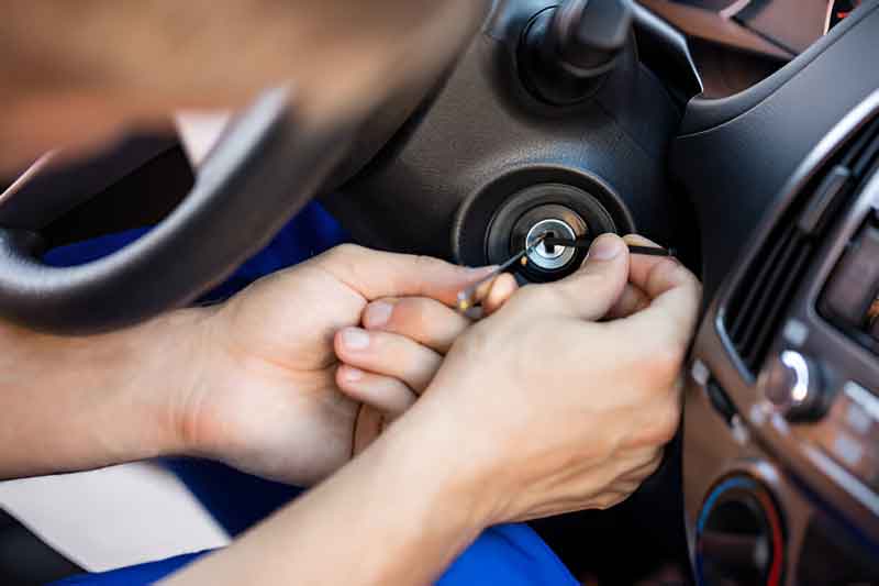 Locksmith repairing a car ignition lock cylinder from the driver seat