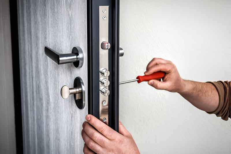 Locksmith adjusting a multipoint lock on the edge of a door with a screwdriver