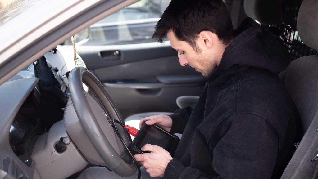 Locksmith programming a car key from the driver seat with a diagnostic tool